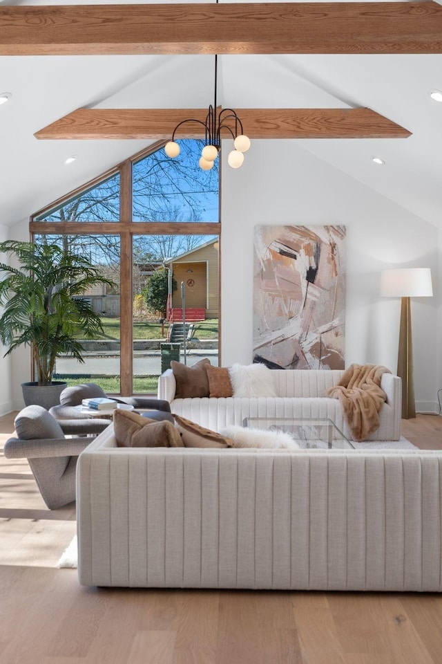 living room featuring lofted ceiling with beams, a chandelier, and light wood-type flooring