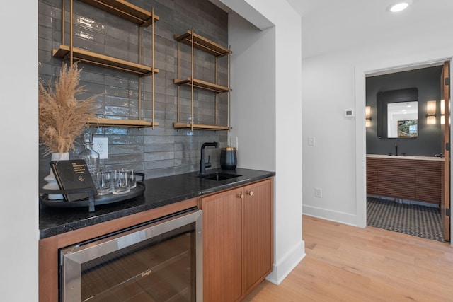 bar featuring sink, light hardwood / wood-style flooring, beverage cooler, and decorative backsplash