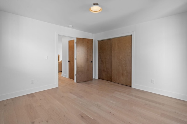 unfurnished bedroom with light wood-type flooring and a closet