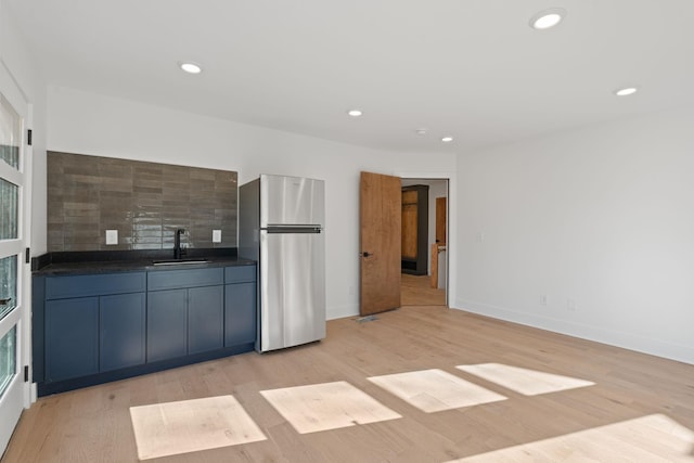 kitchen with sink, decorative backsplash, stainless steel fridge, and light hardwood / wood-style floors