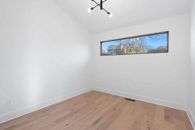 empty room with vaulted ceiling and light hardwood / wood-style flooring