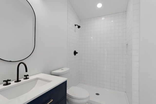 bathroom featuring vanity, a tile shower, and toilet