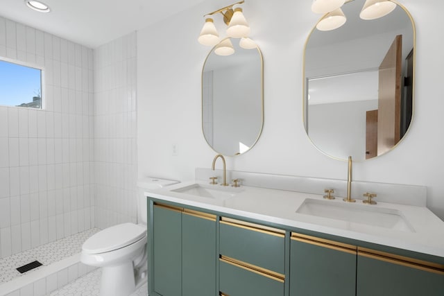 bathroom with vanity, toilet, and a tile shower