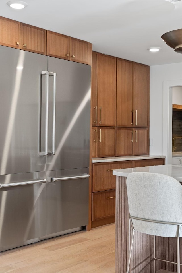 kitchen featuring high quality fridge and light hardwood / wood-style flooring