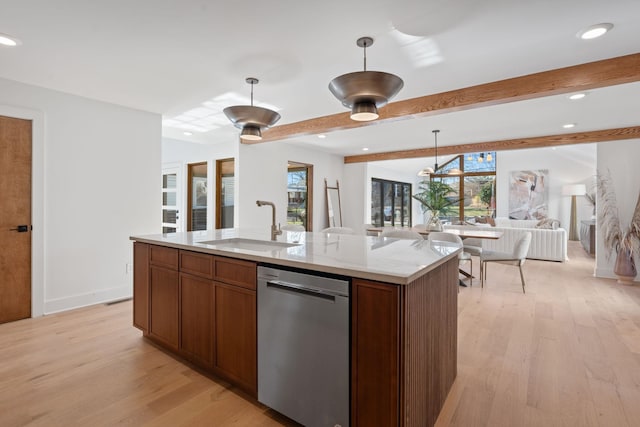 kitchen with hanging light fixtures, dishwasher, light stone countertops, and a kitchen island with sink