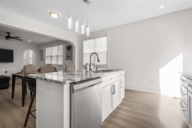 kitchen featuring arched walkways, dishwasher, a breakfast bar, open floor plan, and a sink