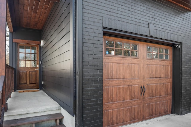 view of exterior entry with a garage and brick siding