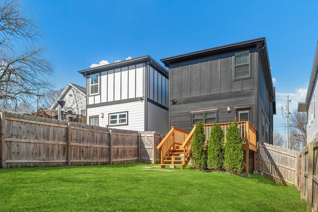 rear view of house with a fenced backyard, a wooden deck, board and batten siding, and a yard