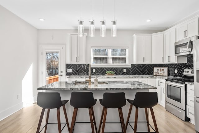 kitchen featuring stone countertops, a kitchen bar, stainless steel appliances, and a sink