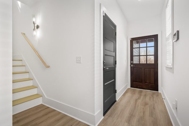 doorway with light wood-style flooring, stairway, and baseboards