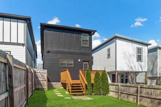 rear view of property featuring a fenced backyard, a gate, a lawn, and board and batten siding