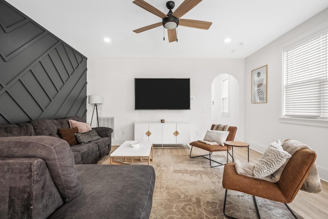 living area with arched walkways, recessed lighting, a ceiling fan, and light wood-style floors