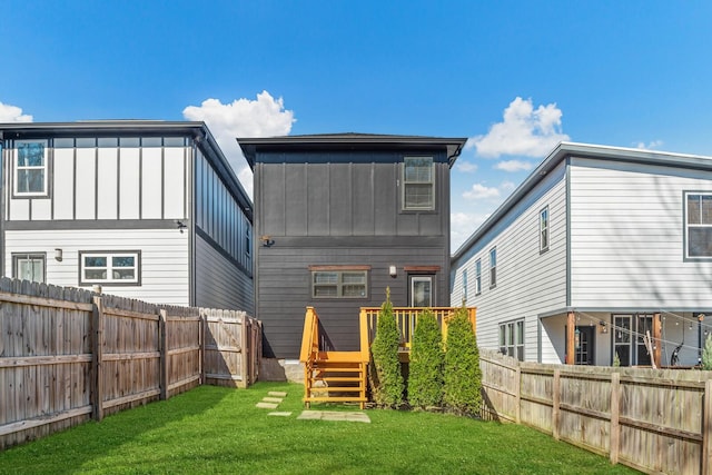 rear view of house with a yard, board and batten siding, a fenced backyard, and a wooden deck