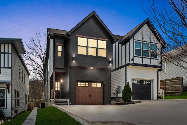 view of front of home with brick siding, concrete driveway, board and batten siding, fence, and a garage