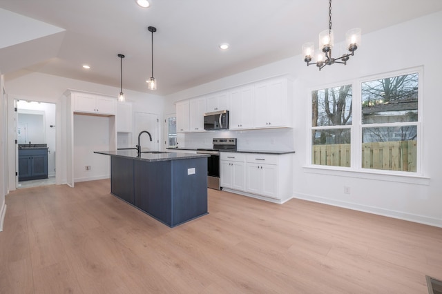 kitchen with pendant lighting, appliances with stainless steel finishes, a kitchen island with sink, and white cabinets