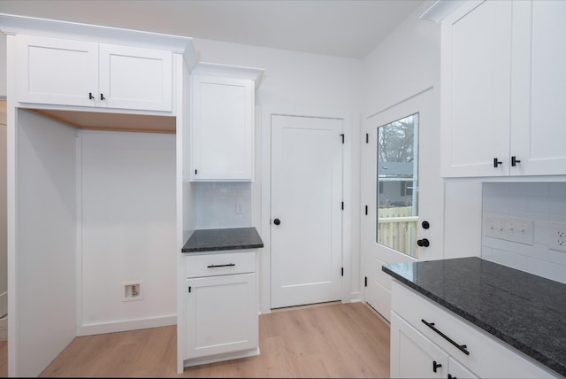 kitchen with light hardwood / wood-style flooring, white cabinets, and dark stone counters