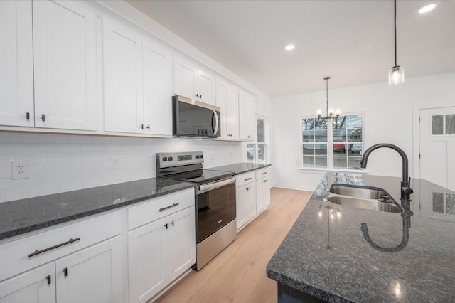 kitchen with sink, white cabinetry, decorative light fixtures, dark stone countertops, and appliances with stainless steel finishes