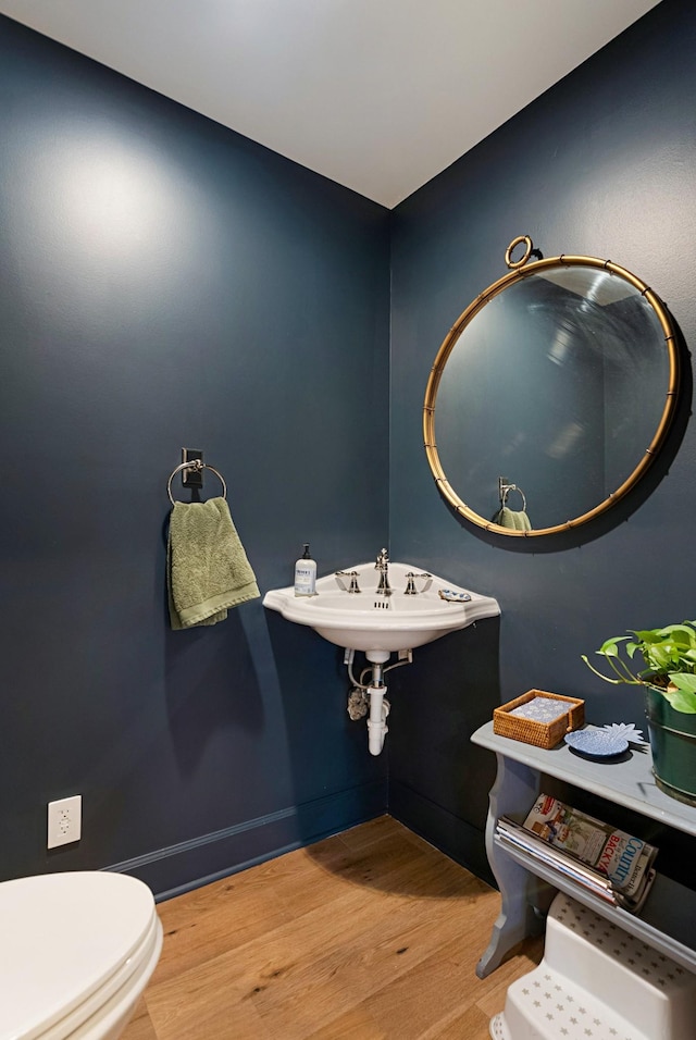 bathroom with a sink, wood finished floors, and toilet