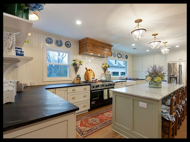 kitchen with range with two ovens, a wealth of natural light, custom range hood, and light wood-style floors