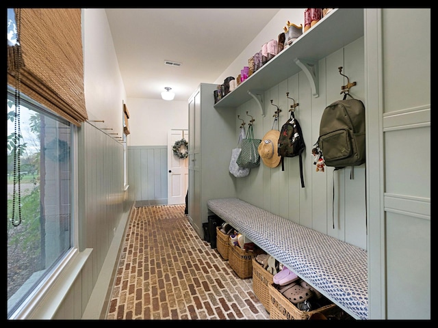 mudroom featuring wainscoting, brick floor, and visible vents