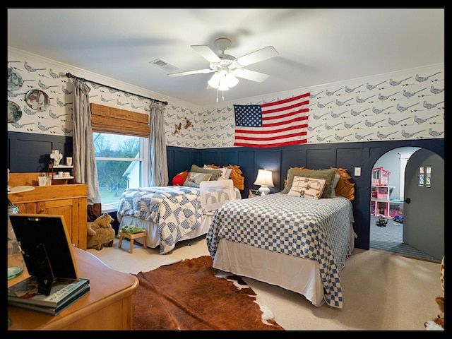 carpeted bedroom featuring ornamental molding, wainscoting, and wallpapered walls