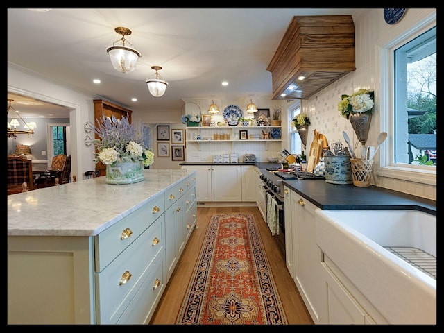 kitchen with open shelves, premium range hood, high end stainless steel range oven, and light wood-style flooring