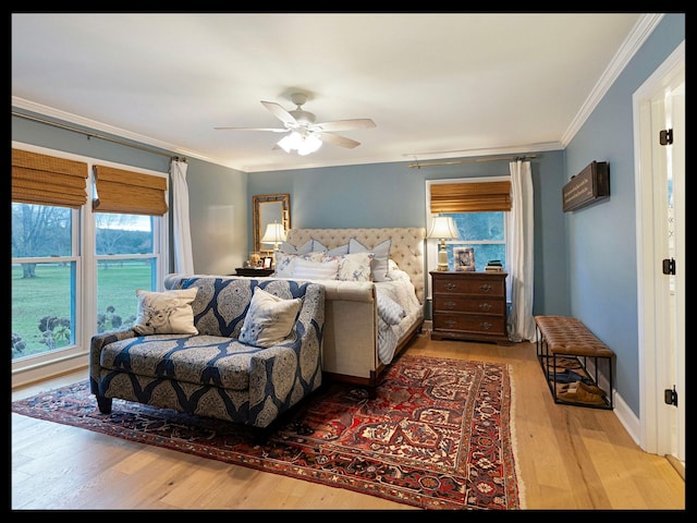 bedroom featuring ceiling fan, light wood-style floors, baseboards, and crown molding