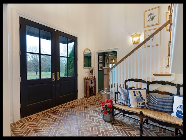 entrance foyer with stairs, french doors, and brick floor