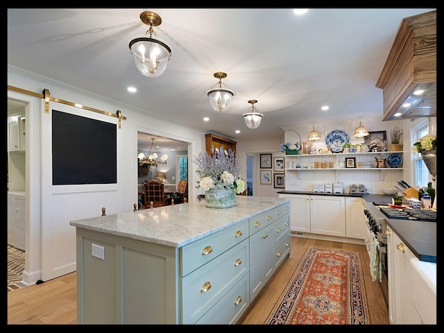 kitchen with a barn door, a kitchen island, light wood-style floors, premium range hood, and open shelves