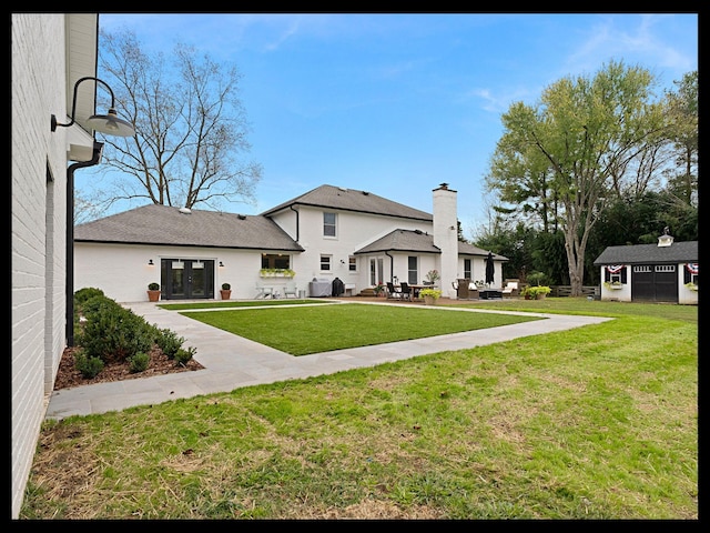 exterior space with a patio area, an outdoor structure, french doors, and a yard