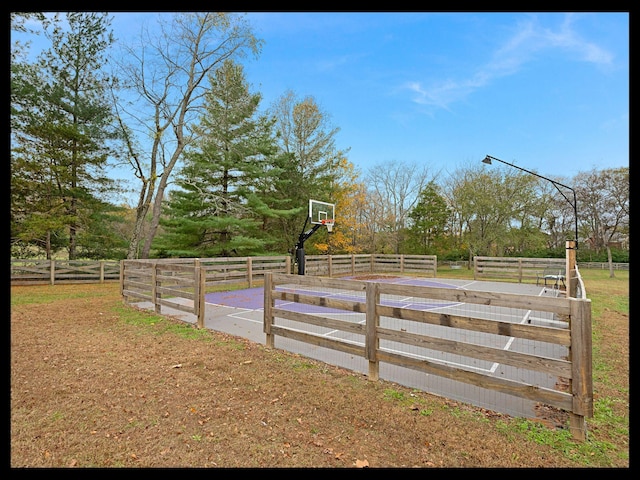 view of yard with basketball hoop and fence