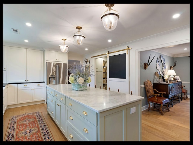 kitchen with light wood finished floors, a barn door, white cabinetry, and stainless steel fridge