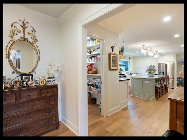 hallway featuring light wood-style floors, crown molding, and recessed lighting