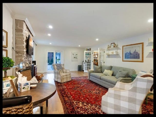 living room featuring a stone fireplace, wood finished floors, and recessed lighting