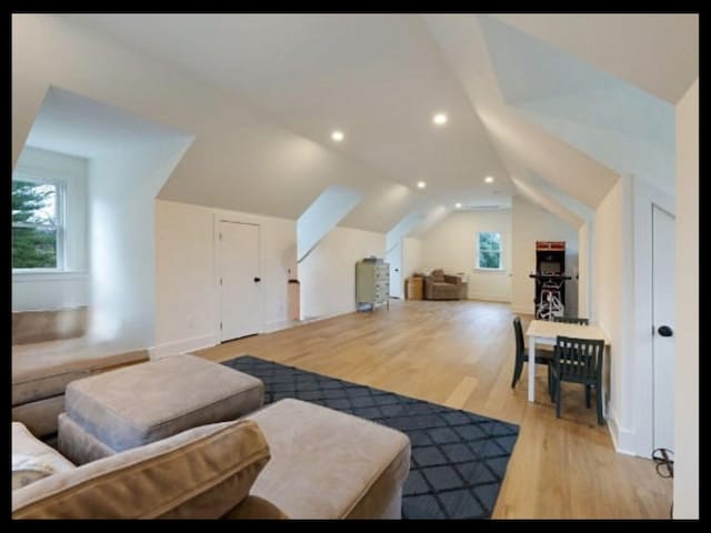 additional living space with vaulted ceiling, light wood-type flooring, and recessed lighting