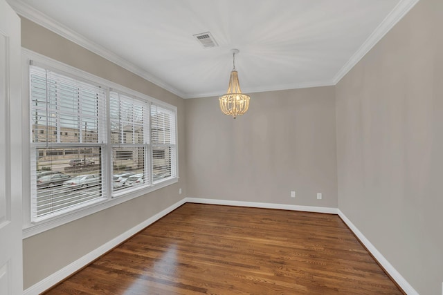 spare room featuring dark wood-type flooring, crown molding, and an inviting chandelier