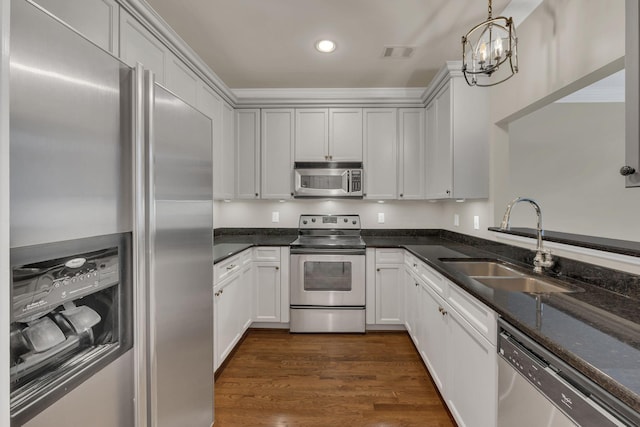 kitchen featuring pendant lighting, sink, appliances with stainless steel finishes, dark stone countertops, and white cabinets