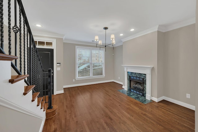 unfurnished living room with crown molding, dark hardwood / wood-style flooring, a chandelier, and a fireplace