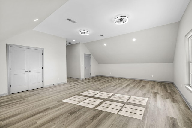 additional living space featuring vaulted ceiling and light wood-type flooring