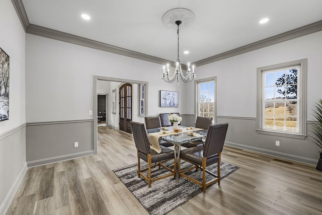 dining room featuring hardwood / wood-style flooring, ornamental molding, an inviting chandelier, and french doors