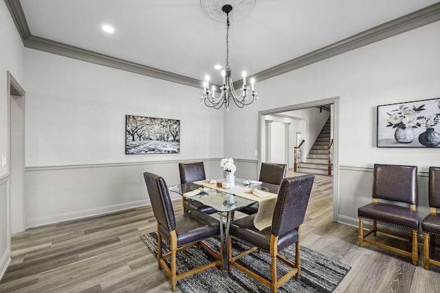 dining area with wood-type flooring, a notable chandelier, and crown molding