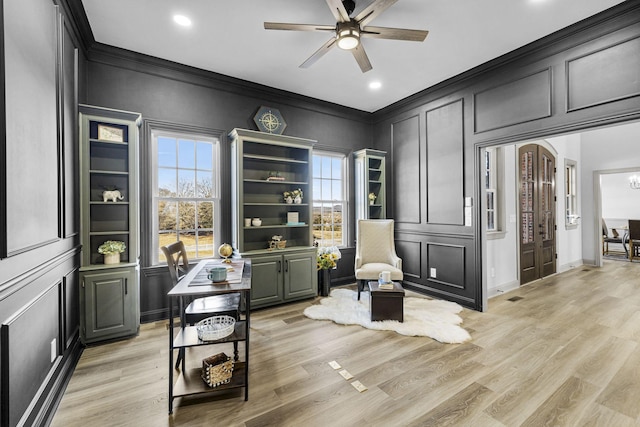 living area with crown molding, ceiling fan, and light hardwood / wood-style floors