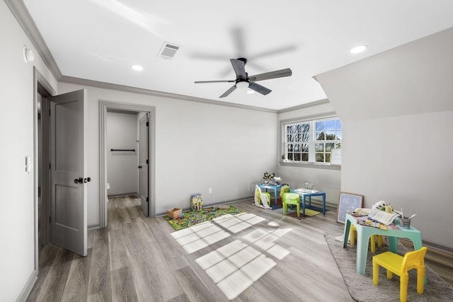 recreation room with ceiling fan, ornamental molding, and light hardwood / wood-style floors