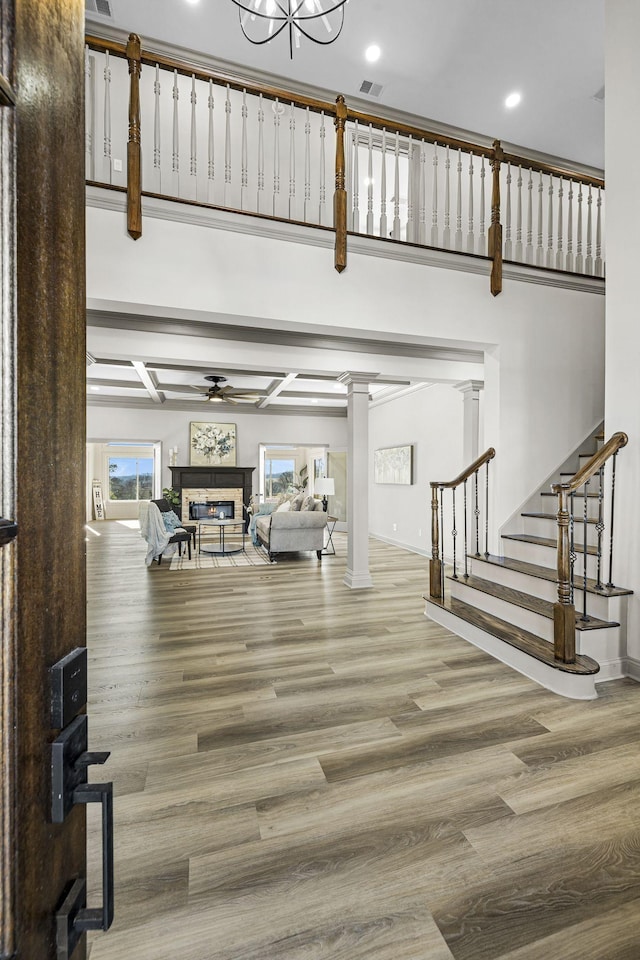 interior space featuring ornate columns, a high ceiling, hardwood / wood-style flooring, and ceiling fan