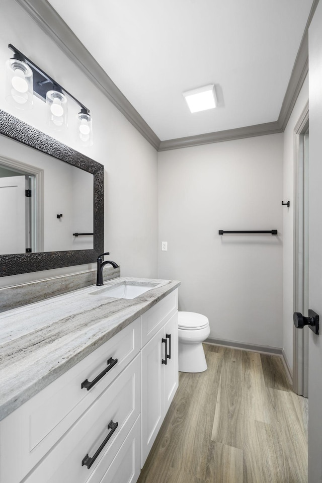 bathroom featuring crown molding, wood-type flooring, vanity, and toilet