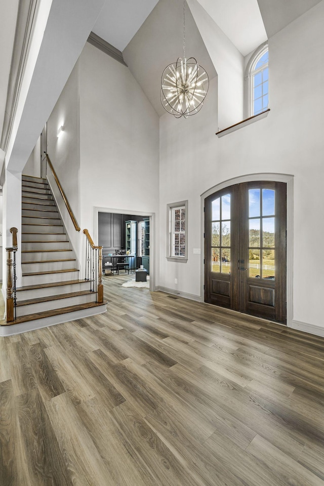 foyer entrance featuring hardwood / wood-style floors, a notable chandelier, a wealth of natural light, and french doors