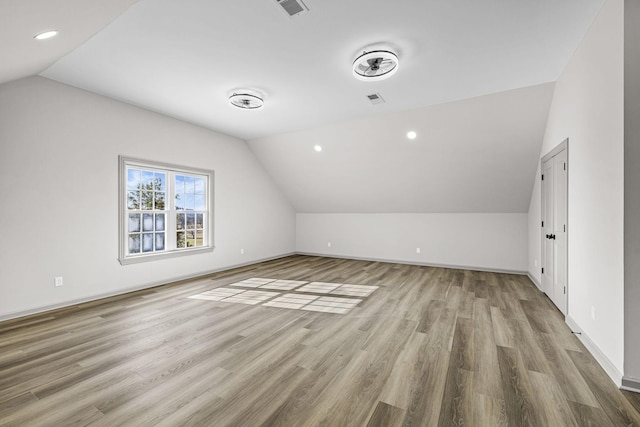 additional living space with lofted ceiling and light hardwood / wood-style flooring