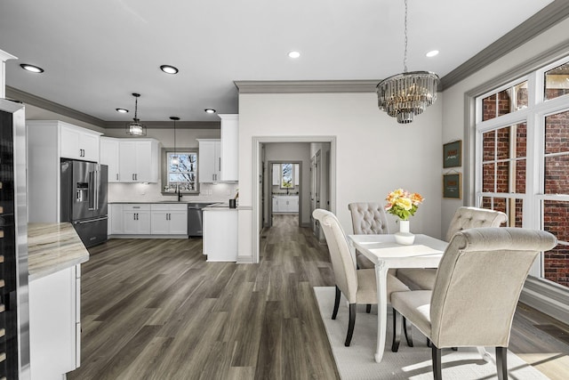 dining area featuring dark hardwood / wood-style flooring, a notable chandelier, crown molding, and sink