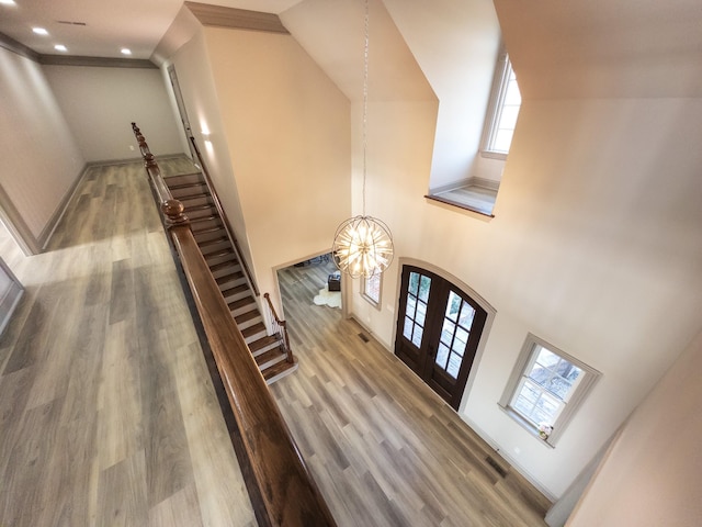 foyer entrance featuring french doors, wood-type flooring, a chandelier, and a high ceiling