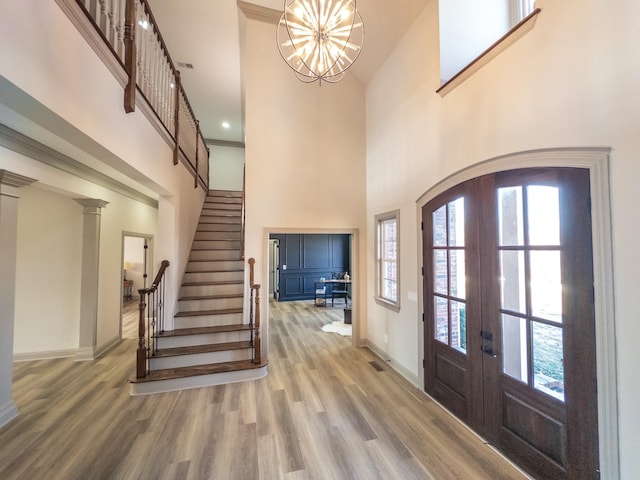 entryway with a high ceiling, hardwood / wood-style floors, a chandelier, and french doors